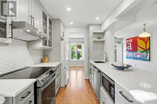 Long galley kitchen with light grey cabinetry, quartz countertops, and stainless steel appliances. - 135 Evelyn Avenue, Ottawa