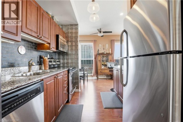 Kitchen with granite countertops, stainless steel appliances, dark tile backsplash, and wood cabinets. - 135 James Street S Unit# 802, Hamilton