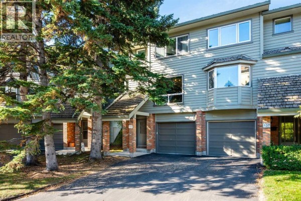 Exterior view of townhouse complex with garages and trees. - 135 Point Drive Nw, Calgary