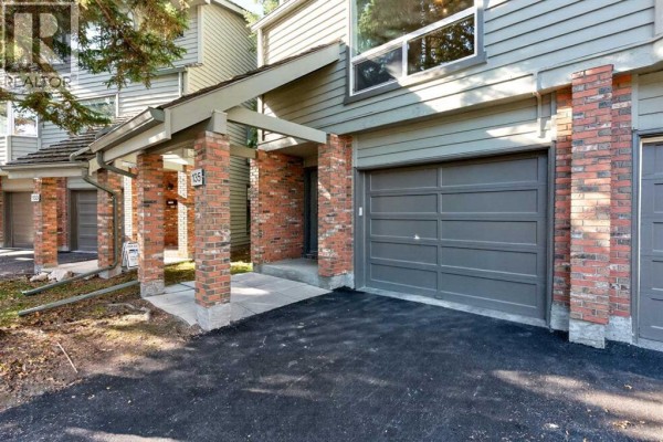 Close-up exterior view of townhouse entrance with brick columns and garage. - 135 Point Drive Nw, Calgary