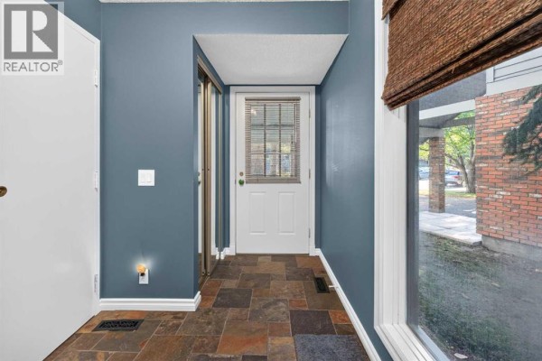 Interior foyer with slate tile floor, blue walls, and front door. - 135 Point Drive Nw, Calgary