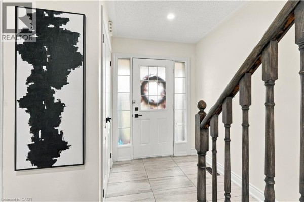 Interior entryway with tile flooring, a dark wood staircase, and abstract art. - 135 Spicebush Terrace, Brampton