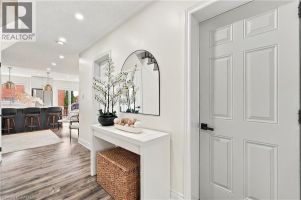 Hallway with white console table, arched mirror, and door leading to kitchen. - 135 Spicebush Terrace, Brampton