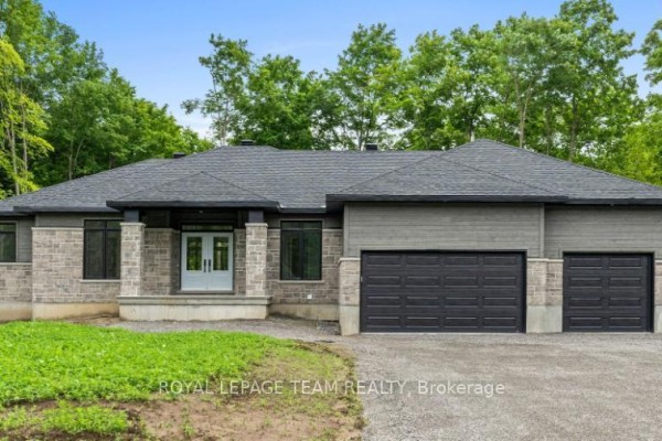 Wide shot of the modern home exterior with stone and grey siding, and a triple garage. - 135 Upton Drive, Beckwith