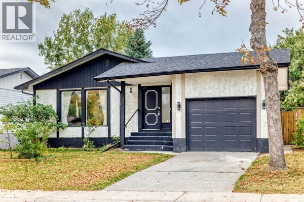 Front exterior of a Calgary home with mature trees and autumn leaves on the lawn. - 135 Whiteview Close Ne, Calgary