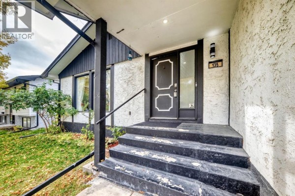Front entrance with black steps, a black door with white geometric accents, and house number 135. - 135 Whiteview Close Ne, Calgary
