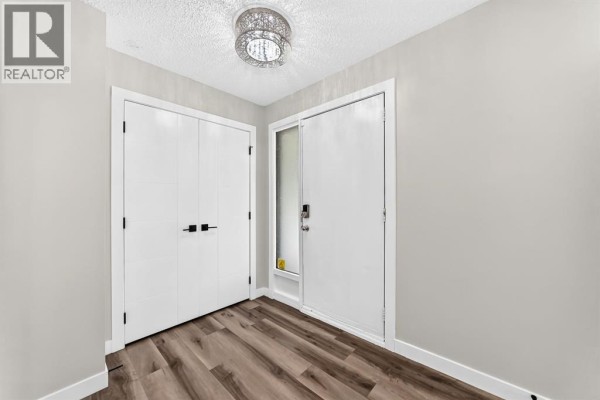 Interior entryway with light grey walls, white doors, and wood-look vinyl plank flooring. - 135 Whiteview Close Ne, Calgary