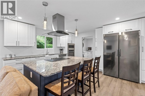 Modern kitchen with white cabinets, granite countertops, large island, and stainless steel appliances. - 1350 Greenwood Way, French Creek