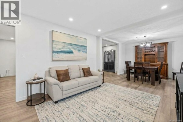 Living room with a beige sofa, large rug, artwork, and view into the dining area. - 1350 Greenwood Way, French Creek