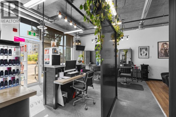 View of the salon's reception desk, styling stations, and product displays from the side. - 1350 St Paul Street Unit# 102, Kelowna