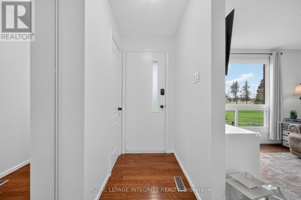 Interior entryway with white walls, hardwood floors, and a white front door with a glass insert. - 1352 Bakker Court, Ottawa