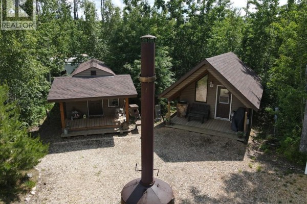 Two small cabins with porches and a large outdoor fireplace in wooded area. - 13520 Township Road 744, Joussard