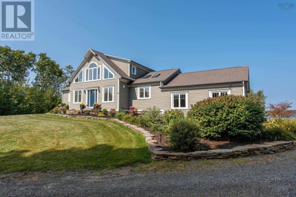 Front exterior of the house featuring a landscaped garden and large windows. - 13573 Highway 6, Wallace Bridge