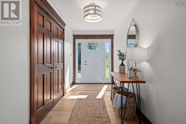 Bright entryway with a console table, light fixture, and natural light from the front door. - 13573 Highway 6, Wallace Bridge