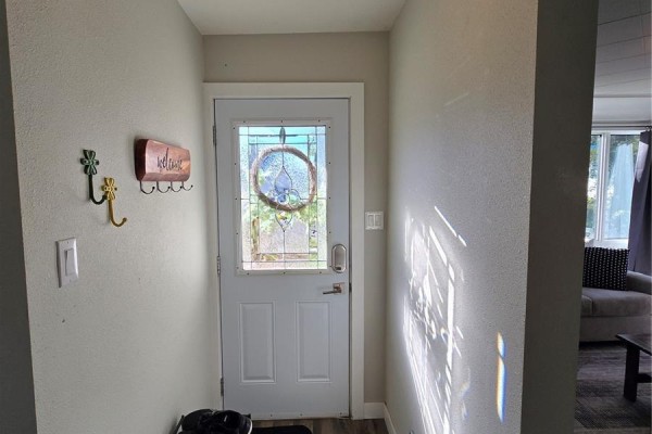 Interior view of a white front door with a stained-glass window and a welcome sign. - 136 10th Street Ne, Weyburn