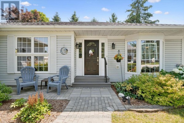 Front entrance of the bungalow featuring a dark brown door, bay windows, and flowering bushes. - 136 Bristlecone Crescent, Centre Wellington