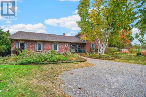 Aerial view of a property surrounded by trees and adjacent to a road intersection. - 136 County 4 Road, Douro Dummer