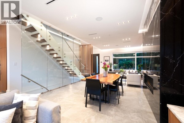 Open-concept living space featuring a glass-encased staircase, dining area, and modern furniture. - 136 E 61st Avenue, Vancouver