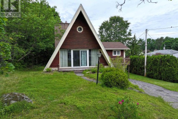 Front exterior of an A-frame house with a lawn and trees. - 136 Empire Street, Bridgewater