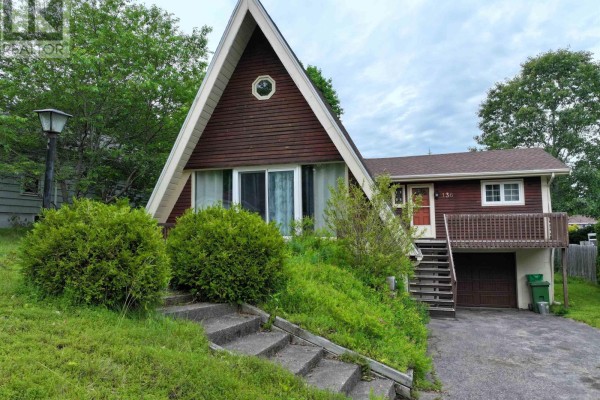 Side view of an A-frame house showing the entrance and driveway. - 136 Empire Street, Bridgewater