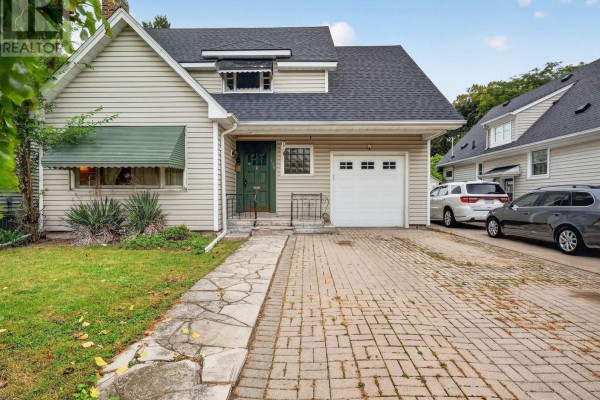Front exterior of the house with a stone walkway leading to the green front door and garage. - 136 Highland Avenue, St  Catharines