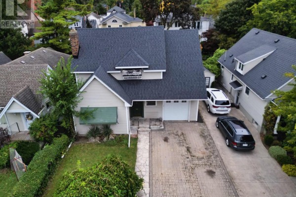 Aerial view of the house showing the roof, driveway, and surrounding lawn and trees. - 136 Highland Avenue, St  Catharines