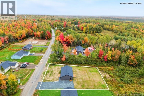 Aerial view of a dark grey house surrounded by a grassy yard and colorful autumn trees. - 136 Horseman Road, Fredericton Junction