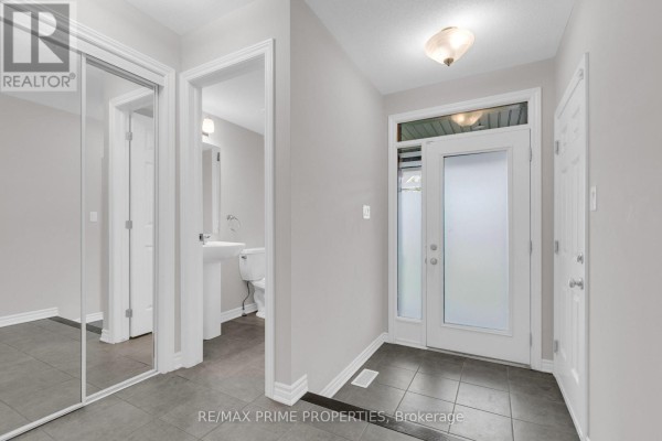 Interior entryway with grey tile floor, white doors, and a glimpse of a toilet and sink. - 136 Lanceleaf Way, Ottawa