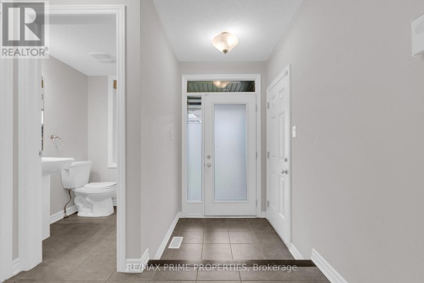 Foyer with grey tile flooring, double glass doors, and access to a bathroom and closet. - 136 Lanceleaf Way, Ottawa