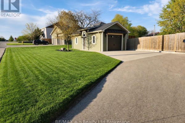 Driveway leading to townhouse garage and detached green structure. - 136 Maple Lane, Tillsonburg