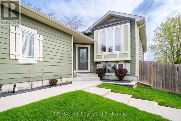 Detached green garage with double doors and concrete driveway. - 136 Maple Lane, Tillsonburg