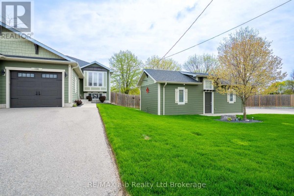 Side view of detached green garage with wood fence and pathway. - 136 Maple Lane, Tillsonburg