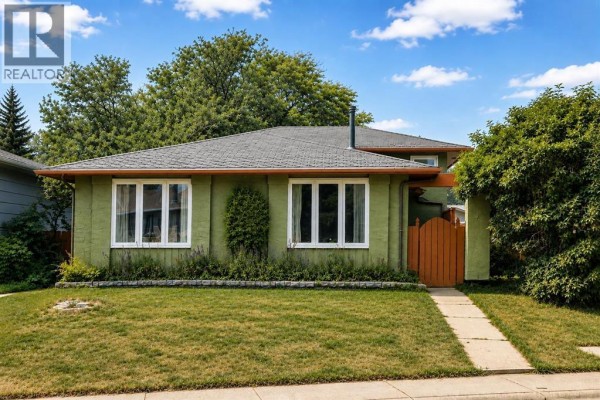 Open concept living and kitchen area with polished wood floors and large windows. - 136 Midlawn Close Se, Calgary