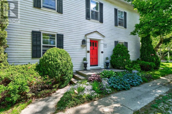 White detached garage with tall evergreen trees and garden in front. - 136 Old Danforth Road, Alnwick/haldimand