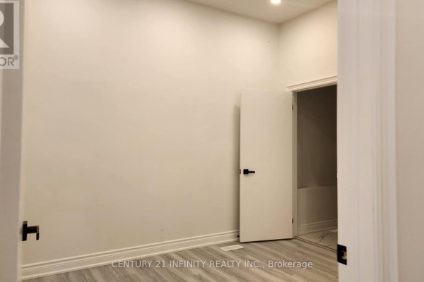 Interior room with white walls, gray flooring, and an open door revealing a bathtub. - 136 Simcoe Street S, Oshawa