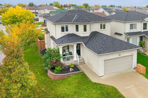 Aerial view of a two-story residential house with a light beige stucco finish and manicured lawn. - 136 Swinford Way, Winnipeg