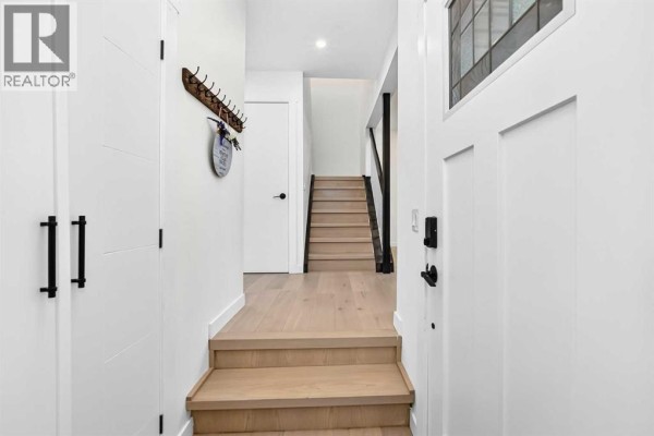 Entrance hall with white doors, a staircase with dark railings, and hardwood flooring. - 136 Templehill Drive Ne, Calgary