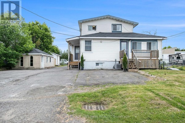 Rear view of a white two-story house with a wooden deck at sunset. - 1368 Labrie Avenue, Ottawa