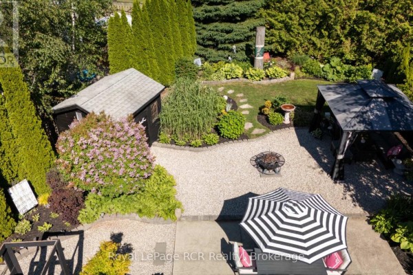 Backyard view showing a fire pit, a black shed, a gazebo, and landscaping. - 137 - 383 Mcnabb Street, Saugeen Shores