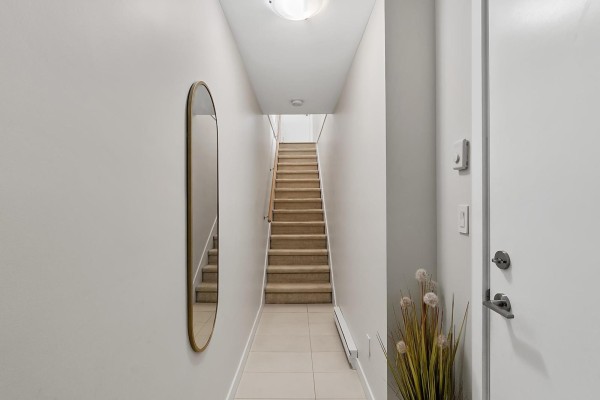 A laundry closet with a stacked white washer and dryer in a hallway. - 137 32633 Simon Avenue, Abbotsford