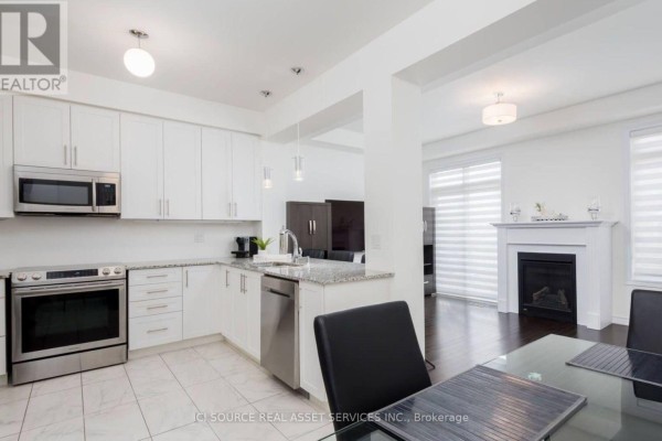Modern white kitchen with granite countertops, stainless steel appliances, and a dining area. - 137 Allegranza Avenue, Vaughan