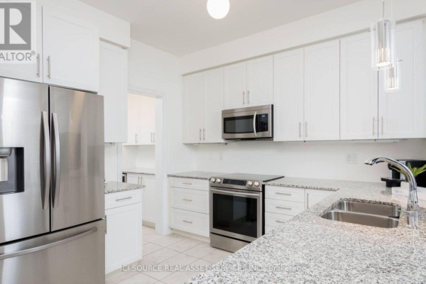Kitchen with white cabinets, granite countertops, stainless steel refrigerator, oven, and microwave. - 137 Allegranza Avenue, Vaughan