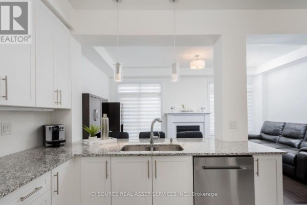 View from kitchen island towards living room fireplace and dark leather sofa. - 137 Allegranza Avenue, Vaughan