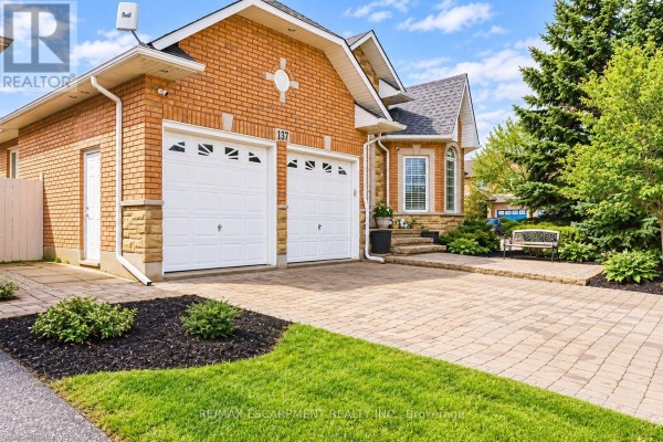 Front view of a brick house with a double garage and stone accents. - 137 Pinehill Drive, Hamilton