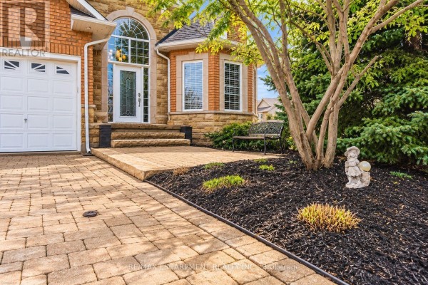 Close-up of a house entrance with a paved walkway, stone steps, and landscaping. - 137 Pinehill Drive, Hamilton