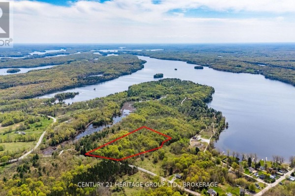 Overhead view of a forested property outlined in red, with a sprawling lake in the background. - 1371 Crow Lake Road, North Frontenac