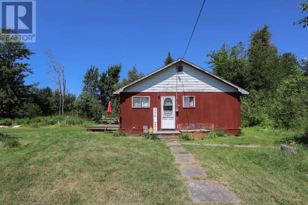 Red cottage with white trim and a covered front porch sits in a grassy yard. - 1371 Sailors Encampment Dr, Richards Landing