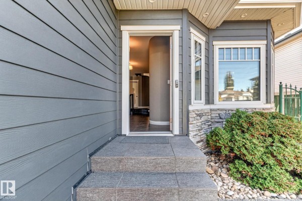 View of the front entrance and doorway of a house with grey siding, stone accents, and granite steps. - 13725 - 131b Avenue Nw, Edmonton