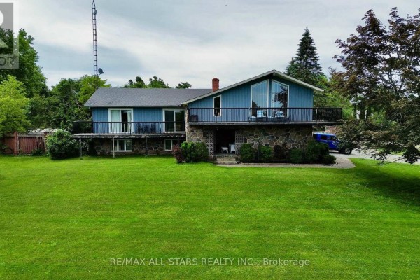 Exterior view of a blue house with stone accents and a large green lawn. - 1374 Regional Road 12 Road W, Brock