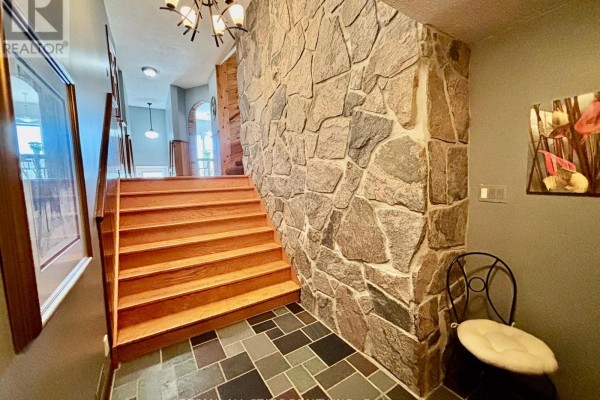 Interior entryway with a large stone wall, wooden staircase, and slate tile flooring. - 1374 Regional Road 12 Road W, Brock